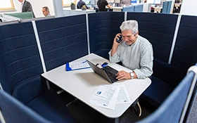 A man on a laptop phone call in a separate work area