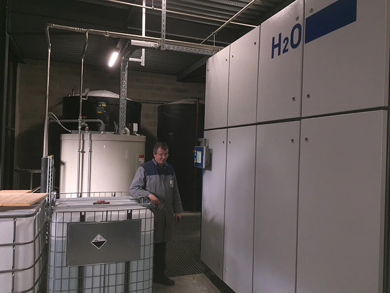 An H2O employee stands next to a VACUDEST system