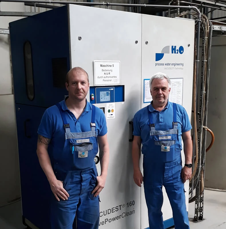 Two H2O employees in front of a water treatment plant